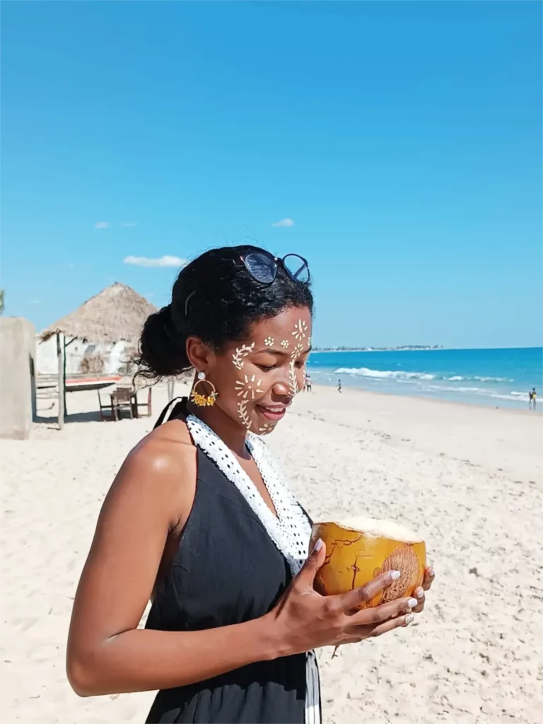 Tiphanie Tsihoarana at the beach holding a coconut.