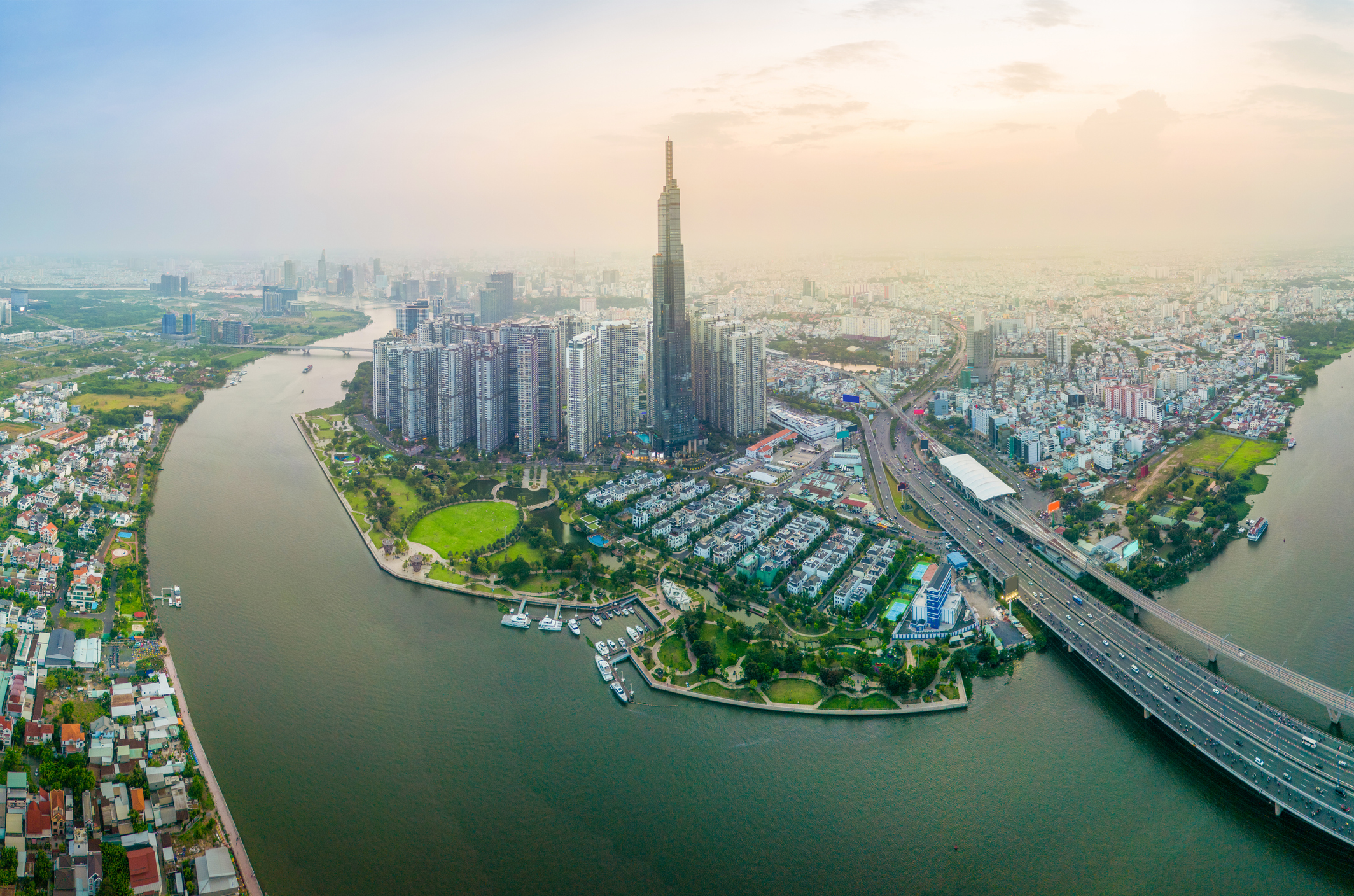 Aerial view of Ho Chi Minh City, Vietnam, with the Saigon River, high-rise towers and highway infrastructure at sunset